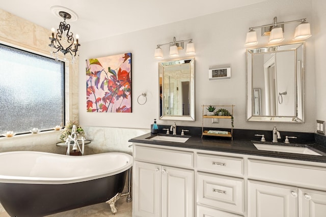 full bath with a freestanding bath, double vanity, a sink, and a chandelier