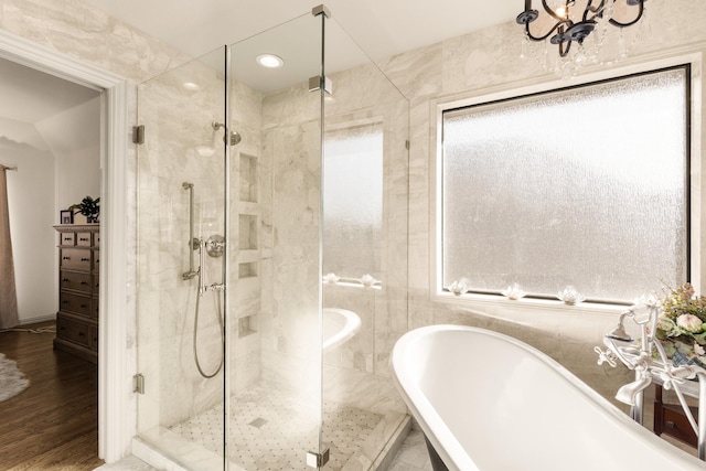 bathroom with a freestanding tub, a shower stall, and wood finished floors