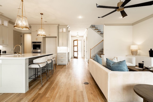 kitchen with a sink, a kitchen breakfast bar, open floor plan, backsplash, and light wood finished floors