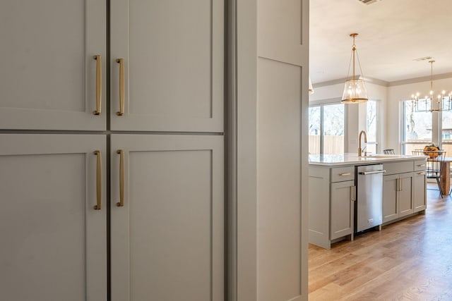 kitchen featuring pendant lighting, a notable chandelier, light countertops, light wood-type flooring, and dishwasher