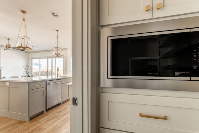 details with a sink, stainless steel appliances, wood finished floors, and visible vents