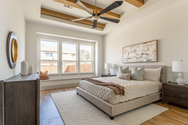 bedroom with beamed ceiling, wood finished floors, visible vents, and a ceiling fan