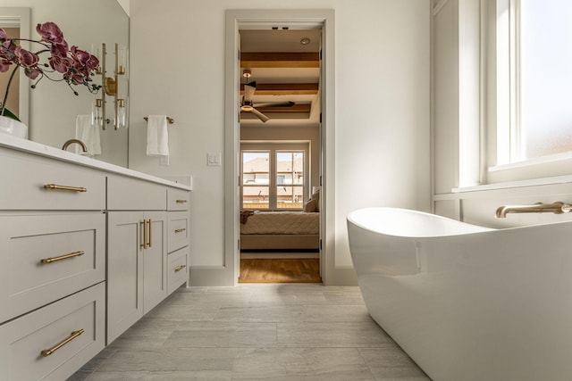 full bathroom featuring ensuite bath, beam ceiling, a freestanding bath, and vanity