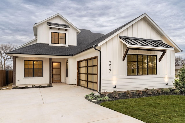 modern farmhouse style home featuring board and batten siding, a standing seam roof, a shingled roof, and a garage