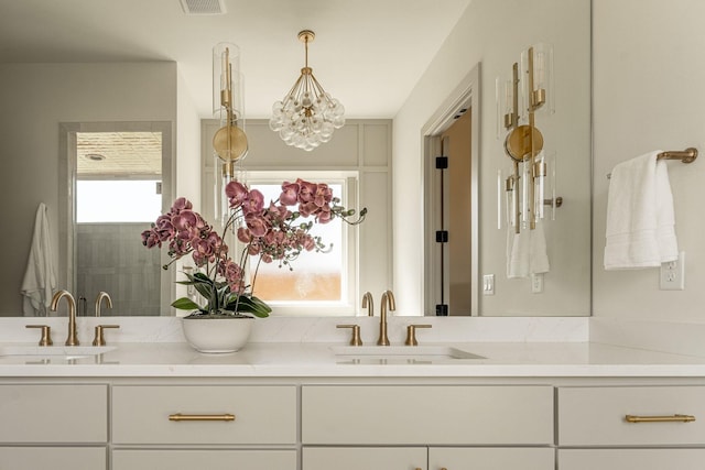 bathroom with double vanity, a notable chandelier, visible vents, and a sink