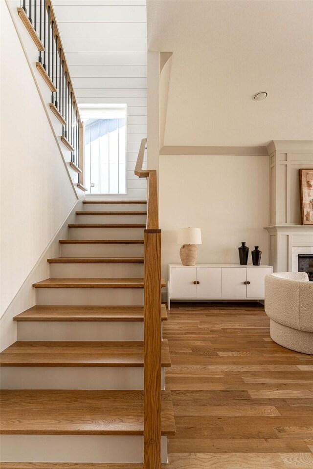 stairs featuring a fireplace and wood finished floors