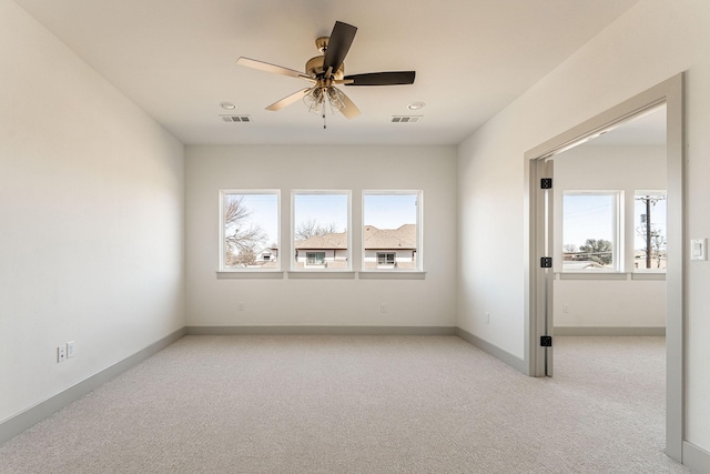 spare room featuring light carpet, baseboards, visible vents, and a ceiling fan