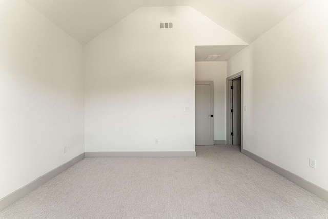 carpeted spare room featuring lofted ceiling, visible vents, and baseboards