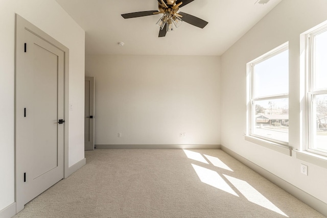 unfurnished room featuring a ceiling fan, light carpet, visible vents, and baseboards