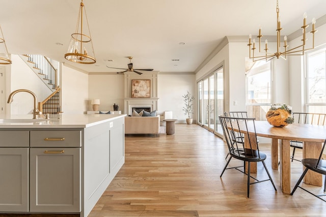 kitchen featuring a fireplace, a sink, light wood-style floors, light countertops, and gray cabinets