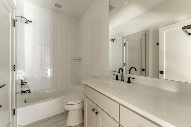 full bath with toilet, shower / bath combination, wood finished floors, visible vents, and vanity