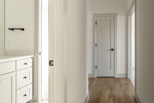 corridor with baseboards and wood finished floors