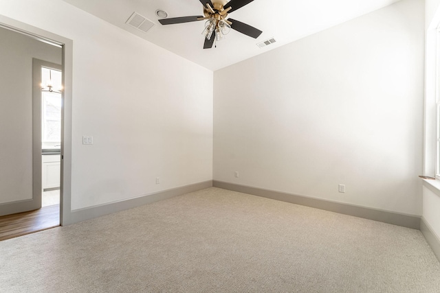 empty room featuring carpet floors, visible vents, ceiling fan, and baseboards