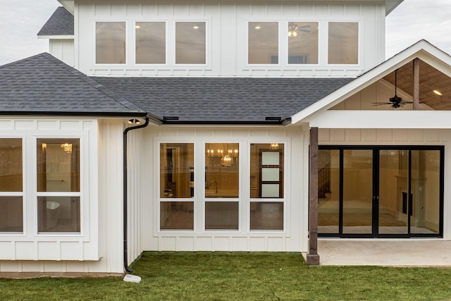 back of property featuring board and batten siding, roof with shingles, a yard, and a ceiling fan