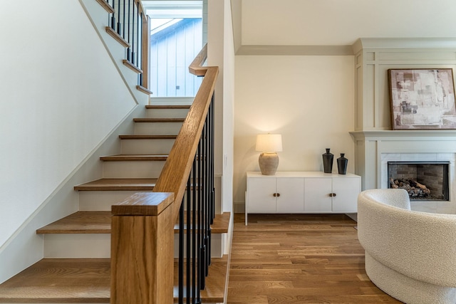 stairs featuring a fireplace and wood finished floors