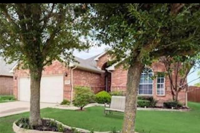 ranch-style home with driveway, a garage, fence, a front lawn, and brick siding