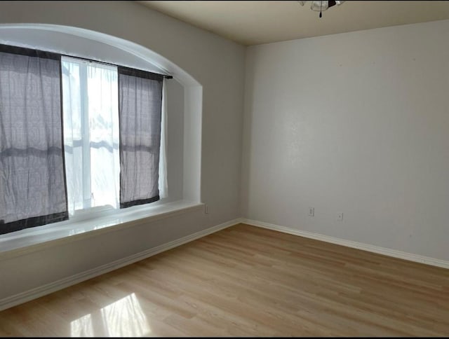 unfurnished room with light wood-style flooring and baseboards