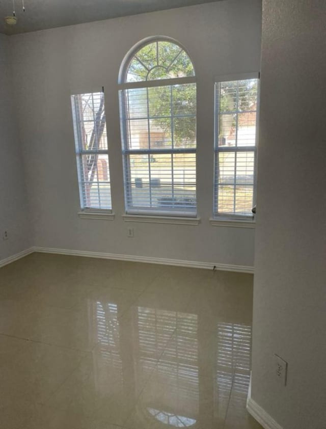 tiled spare room featuring baseboards