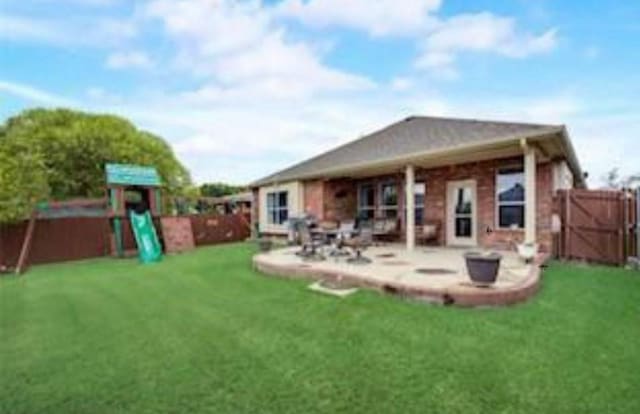 rear view of house featuring a yard, fence, a playground, and a patio