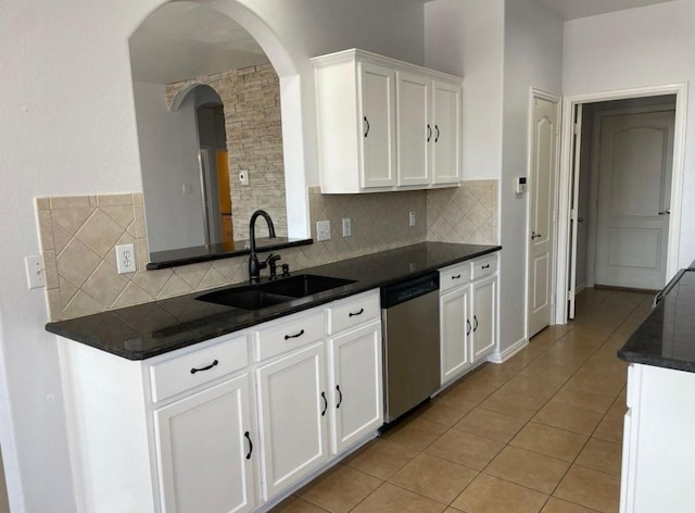 kitchen featuring light tile patterned floors, tasteful backsplash, stainless steel dishwasher, white cabinetry, and a sink