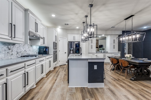 kitchen featuring visible vents, white cabinets, appliances with stainless steel finishes, light wood-type flooring, and under cabinet range hood