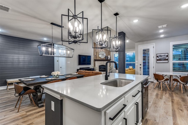 kitchen featuring a fireplace, a sink, white cabinetry, visible vents, and light wood-style floors