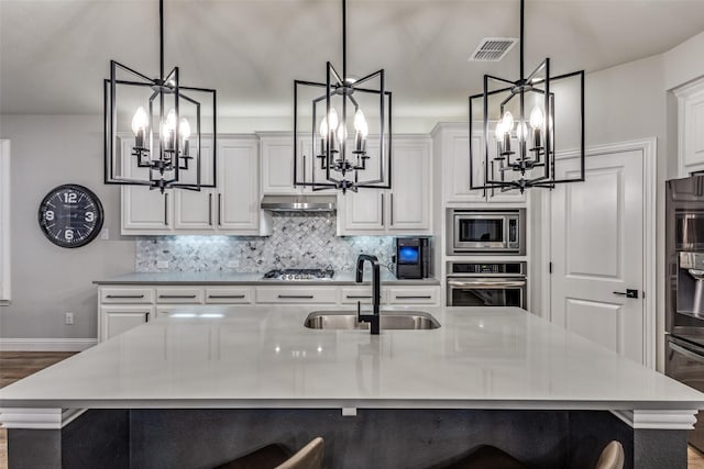 kitchen with tasteful backsplash, stainless steel appliances, a kitchen bar, a chandelier, and a sink