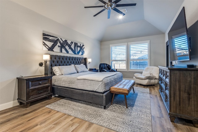 bedroom featuring a ceiling fan, vaulted ceiling, baseboards, and wood finished floors