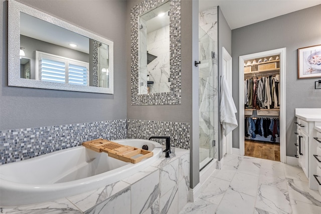 bathroom with marble finish floor, a spacious closet, vanity, a shower stall, and a bath