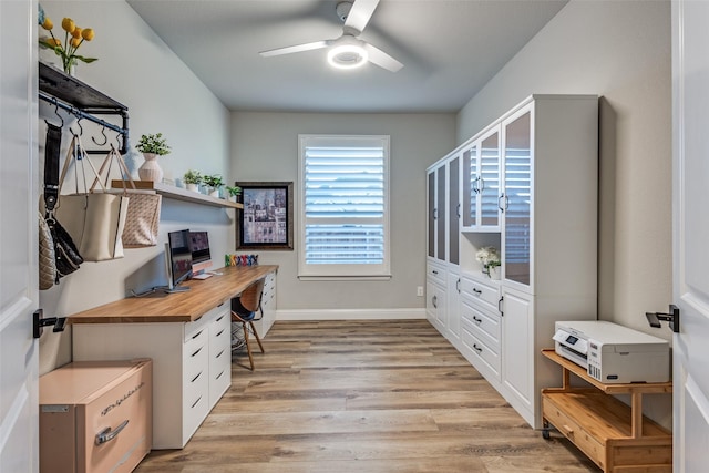 office area with light wood-type flooring, a ceiling fan, and baseboards