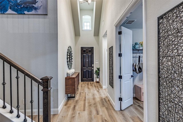 foyer entrance with a high ceiling, wood finished floors, visible vents, and baseboards