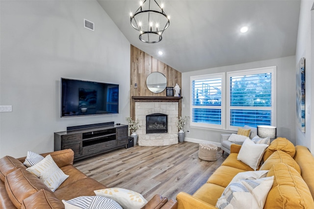 living room featuring visible vents, a chandelier, wood finished floors, a fireplace, and high vaulted ceiling