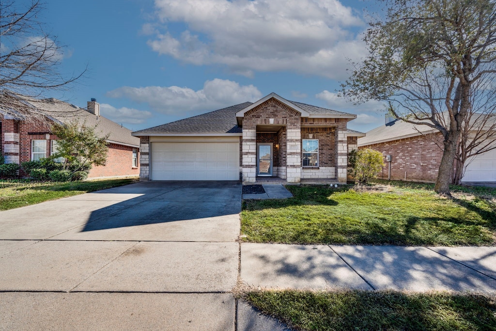 single story home with concrete driveway, stone siding, an attached garage, a front yard, and brick siding
