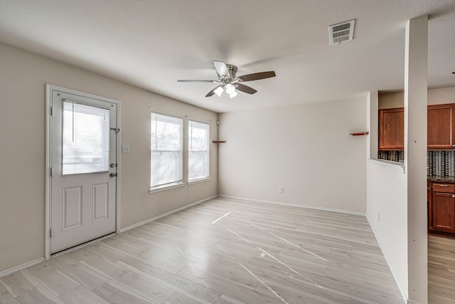 interior space featuring ceiling fan, baseboards, visible vents, and light wood-style floors