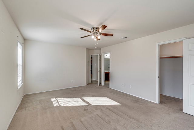 unfurnished bedroom featuring visible vents, a ceiling fan, ensuite bathroom, a spacious closet, and carpet flooring