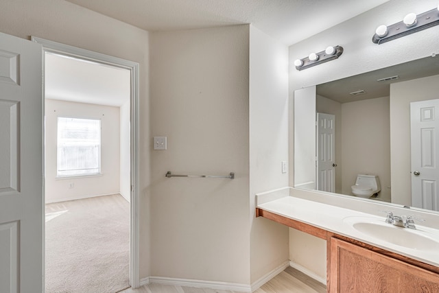 bathroom with visible vents, vanity, toilet, and baseboards