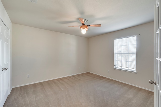 unfurnished room with baseboards, a ceiling fan, and light colored carpet