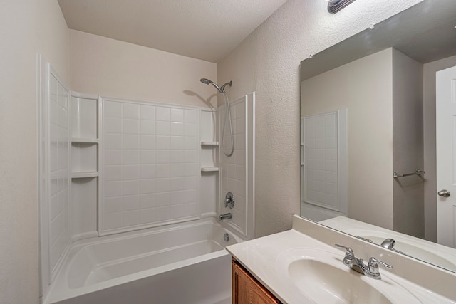 bathroom with a textured wall, bathtub / shower combination, and vanity