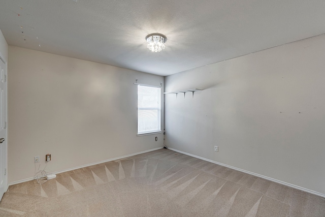 carpeted empty room featuring a textured ceiling and baseboards