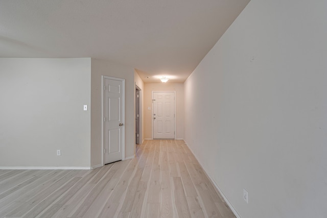 hallway featuring light wood finished floors and baseboards