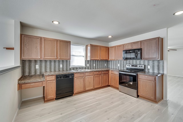 kitchen with light wood finished floors, baseboards, backsplash, black appliances, and a sink