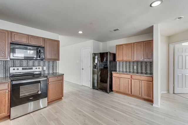 kitchen with black appliances, tasteful backsplash, visible vents, and light wood finished floors