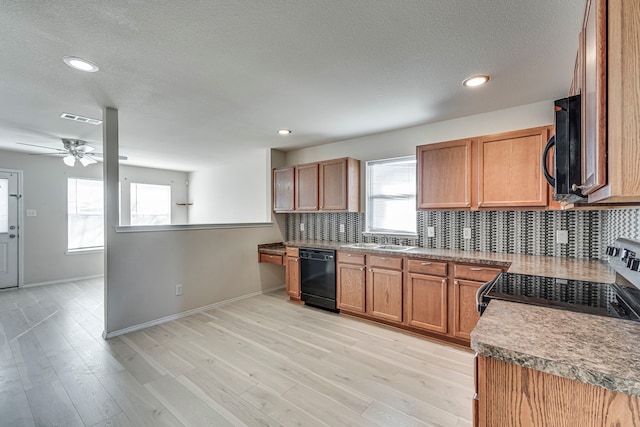 kitchen with light wood-style flooring, a sink, visible vents, black appliances, and tasteful backsplash