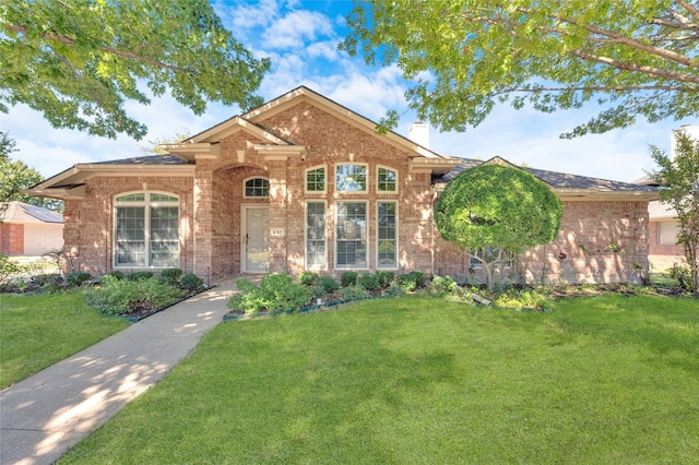 ranch-style house with brick siding, a chimney, and a front lawn