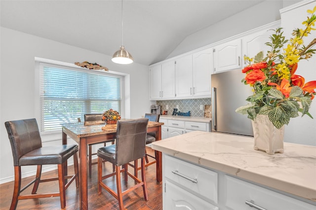 kitchen with dark wood-type flooring, white cabinets, light stone countertops, tasteful backsplash, and pendant lighting