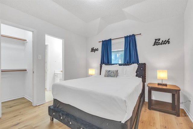 bedroom with a closet, baseboards, vaulted ceiling, and light wood finished floors