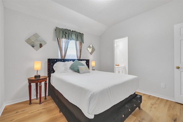 bedroom with lofted ceiling, a textured ceiling, light wood-type flooring, and baseboards