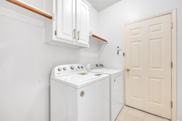 laundry area with light tile patterned floors, washer and clothes dryer, and cabinet space