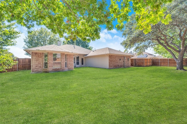 back of property featuring brick siding, a yard, a chimney, and a fenced backyard