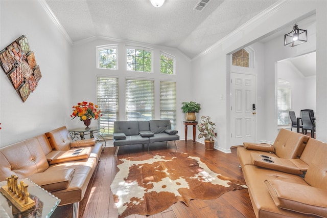 living area with vaulted ceiling, hardwood / wood-style floors, visible vents, and crown molding